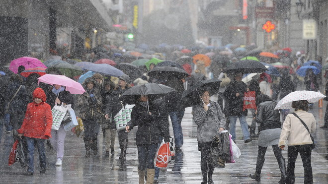 people holding umbrellas under heavy rain