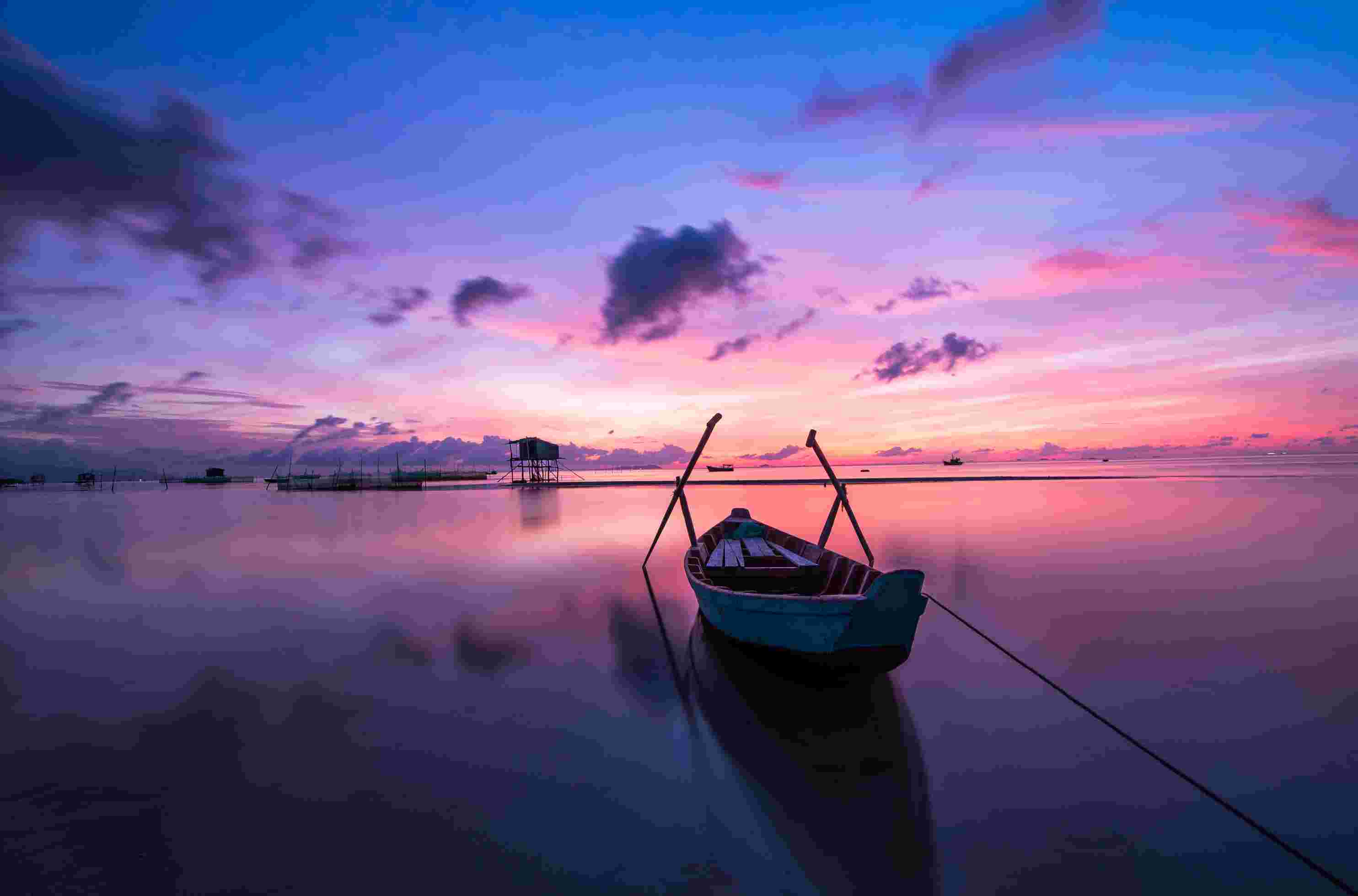 A boat on a river under a purple and bluish cloudy weather